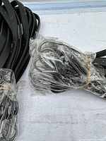 Close-up image of bundled black rubber bungee cords with visible silver metal hooks wrapped in plastic.