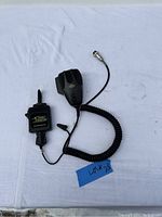 Both Cobra CB mic and Gear Keeper mic tether laid out on white cloth background, showing coiled cords and connectors.