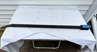 Metal ratchet bar laid flat on a white fabric surface, showing full length of bar