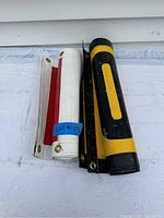 Two rolled mesh banners, yellow & black and white & red, showing brass grommets and edges.