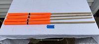 Four orange fluorescent mesh load flags laid horizontally on a white surface, showing full wooden poles and mesh flags, labeled with taped note 'Lot 9'