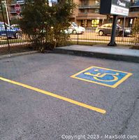Parking lot with freshly painted handicap symbol and yellow line striping on asphalt surface