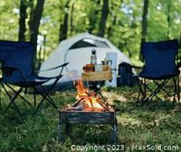 Tent, folding chairs and a portable fire pit in a wooded campsite