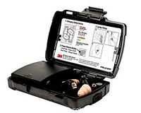 Open black carrying case showing tan ear tips seated in built-in charger and instruction diagram inside lid