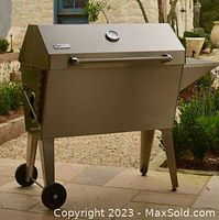 Assembled grill with closed lid showing stainless steel body, wheels and legs