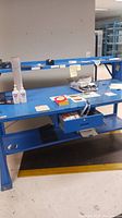Full view of the blue metal work desk with items on surface and shelves