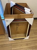 Box of five rich brown picture frames with gold inner edge and corner protectors.