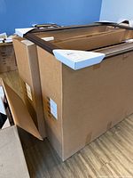 Large rectangular wooden picture frames packed in cardboard boxes with corner protectors.