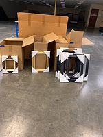 Multiple 8x10 picture frames of various colors and sizes placed on a concrete floor near boxes.
