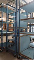 Image showing multiple tall blue metal shelving racks with adjustable shelves placed in a large indoor space.