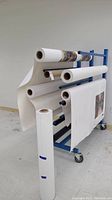 Overall view of blue metal rack with multiple canvas rolls