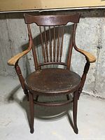 Front view showing carved sunburst motif on the backrest and curved armrests with natural wear.