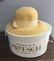 Yellow felt ladies hat on white branded oval hat box
