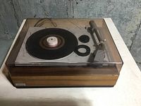 Front angle view of Lenco record player with clear dust cover showing wooden base and black rubber mat.