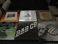 Photo showing 6 vinyl records with album covers from classic rock bands like Lynyrd Skynyrd, Bad Company, and Three Dog Night on a table.