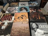 Photo shows 12 vinyl record albums spread out in 3 rows of 4 on a table. Covers include photos and artwork of notable 70s-80s musicians such as Diana Ross, Bee Gees, Pointer Sisters, and ABBA.