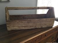 Front angled view of the rustic handmade wooden toolbox showing open top and grain details.