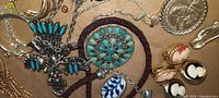 Close-up of various turquoise stone brooches, cameo pins, and blue and white enamel jewelry pieces.
