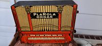 Front view of the PlaRola Organ showing printed keyboard and pipes with text.