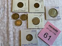 Lot of eight vintage coins including Indian Head Pennies, Buffalo Nickels, War Nickels, Mercury Dime, and Half Dollar all visible in a single image on a white cloth.