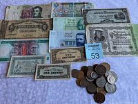 Photo showing assortment of foreign banknotes including Canadian, Japanese Government, Israeli, Mexican Pesos, and a German mark note, alongside a pile of assorted coins.