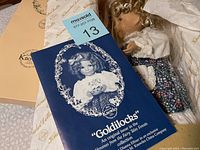 Doll with original box and brochure showing vintage photo and branding.