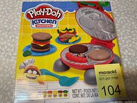 Front box image showing Play-Doh Kitchen Creations cooking set with molded food items and spatula accessory.