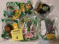 Full set of six sealed Happy Meal Wizard of Oz 75th Anniversary toys in original packaging, arranged on surface.