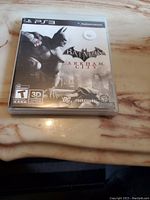 Front cover of the Batman Arkham City game case for PS3 showing Batman and Gotham City graphics.