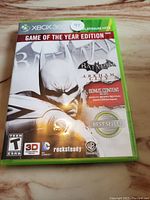 Front cover of Batman Arkham City Xbox 360 Game of the Year Edition showing cover art and bonus content labels.