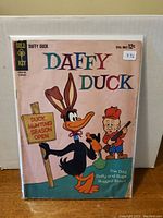 Comic book cover showing Daffy Duck in rabbit ears holding a sign 'Duck Hunting Season Open' with a hunter character, title and price visible.
