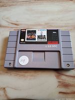 Front view of the gray SNES cartridge showing the NBA Showdown label intact with minor wear, handwritten white sticker '29' on lower left, and number marking on the front housing.