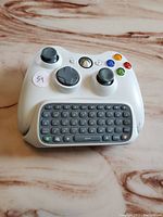 Top view of white Xbox 360 controller with attached black and gray chatpad keypad showing standard buttons and QWERTY keys.