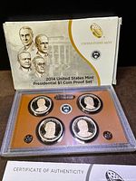 Display of the 2014 US Mint Presidential $1 Coin Proof set in its original box, showcasing four proof coins representing presidents, along with the COA visible in front.