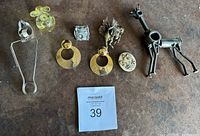 Full lot view showing various brooches and earrings on a dark surface, including a giraffe brooch, Pegasus brooch, earrings, and flower-shaped brooch.
