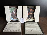Pair of collectible plates in cardboard holders with corresponding Certificates of Authenticity laid in front