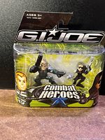 Front view of boxed G.I. Joe Combat Heroes figures showing Duke and Baroness in packaging with green and black graphic design.