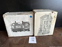 Two boxes of Heather Harness Heritage Village Collection miniature buildings, one labeled Post Office, both show wear and staining.