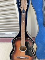 Full front view of sunburst acoustic guitar in open hard case