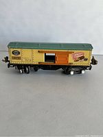 Side view of Lionel Baby Ruth train car showing yellow body, green roof, orange sliding door, and Baby Ruth logo with model number 1679.