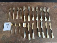 Full set of silverware laid out showing mother of pearl handles and variety of forks, knives, and spoons.