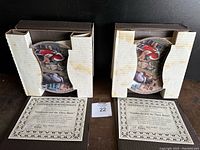 Two decorative plates in protective cardboard packaging with visible Certificates of Authenticity beneath each box.