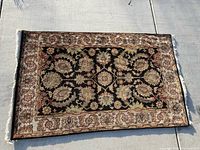 Full view of rug laid flat showing black field and beige border