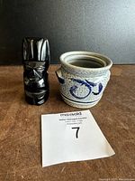Photo showing front view of tiki statue and blue and white ceramic pot.