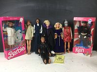 Full lot view of assorted Barbie, Ken, and other dolls, including Navy Barbie and Marine Ken in original packaging, with several loose dolls beside them.