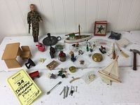 Photo showing the assortment of dollhouse miniatures and small items spread out, including the soldier figure, miniature boats, furniture, animals, and small tools.