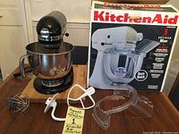 Mixer on wood surface with bowl, attachments and box