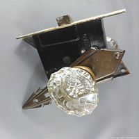 Close-up view of one clear prismatic glass door knob attached to the metal locking mechanism showing detailed facets and brass hardware.