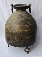 Full front angle view of entire jug showing overall shape, decorative patterns, handles and feet.