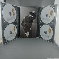 Open Michael Jackson CD box set showing 8 discs with gold silhouette images of Michael Jackson on a white background.